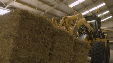 A-large-machine-picks-up-a-massive-hay-bale