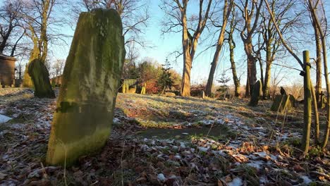 FPV-flying-around-headstones-in-autumn-sunrise-snowy-churchyard-cemetery-during-golden-hour