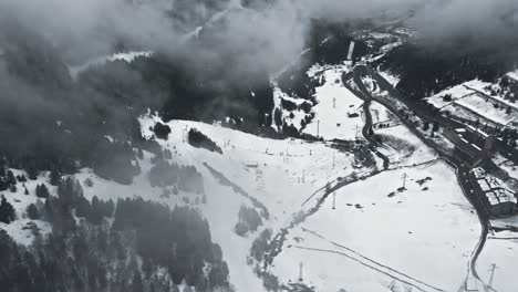 Aerial,-empty-ski-resort-in-a-cloudy-misty-mountain-valley-during-COVID-19-pandemic
