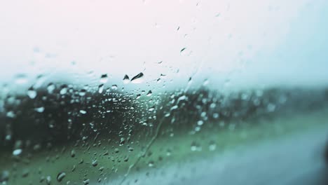 Rains-drops-on-car-window-traveling-along-a-country-road