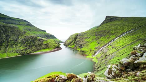 Fjord-surrounded-by-green-mountains-and-moving-clouds-timelapse