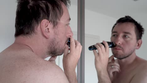 Hombre-Afeitándose-La-Barba-Frente-A-Un-Espejo-Con-Una-Maquinilla-De-Afeitar-Eléctrica