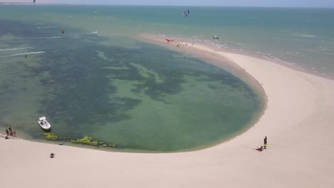 Drone-footage-of-two-people-on-the-beach-watching-kitesurfers-in-Dakhla,-Morocco