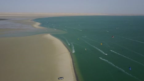 Drone-shot-of-kiteboarders-surfing-on-the-coast-of-Dakhla,-Morocco