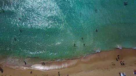 Drone-view-of-white-sand-beach,-umbrellas-and-tourists-in-Falassama-beach,-Crete-Greece