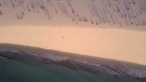 Drone-footage-of-beachgoers-lining-the-sand-in-Jericoacoara,-Brazil