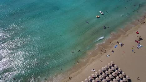 Drone-view-of-white-sand-beach-with-tourists-in-Falassama-beach,-Crete-Greece