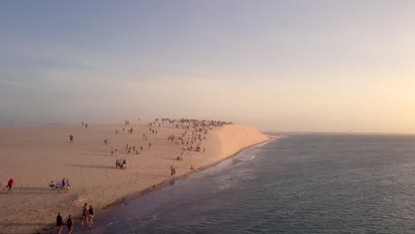 Drone-shot-of-beachgoers-watching-the-sunset-in-Jericoaoara,-Brazil