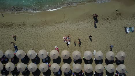 Drone-footage-of-four-friends-laying-in-the-sand-then-revealing-the-white-sand-Falassama-Beach-in-Crete,-Greece