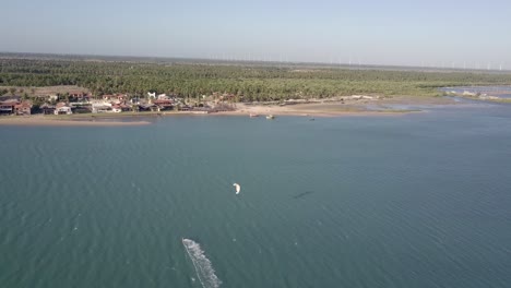 Drone-following-a-Kite-Boarder-panning-up-to-the-landscape-of-Ilha-do-Guajiru,-Brazil