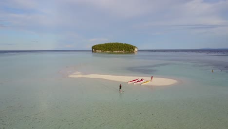 Drone-footage-zooming-over-paddle-boarders-in-to-an-island-in-Raja-Ampat,-Indonesia