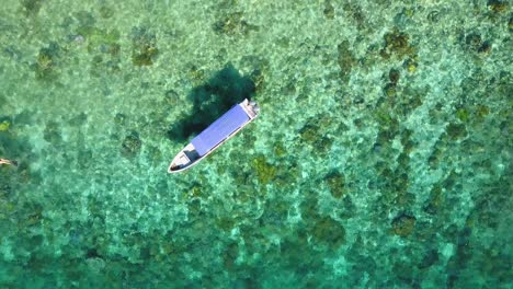 Drone-footage-of-divers-swimming-next-to-a-boat-in-tropical-Raja-Ampat,-Indonesia