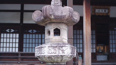 Antiguo-Farol-De-Piedra-Japonés-Sentado-Frente-A-Un-Antiguo-Templo-En-Kyoto,-Japón-Primer-Plano
