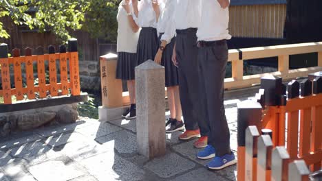 Students-on-vavation-taking-a-group-picture-in-fron-of-a-small-bridge-in-Kyoto,-Japan-soft-lighting-slow-motion-4K