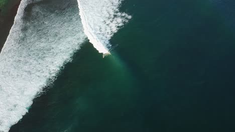 Drone-footage-of-surfers-riding-waves-in-Uluwatu,-Bali-Indonesia