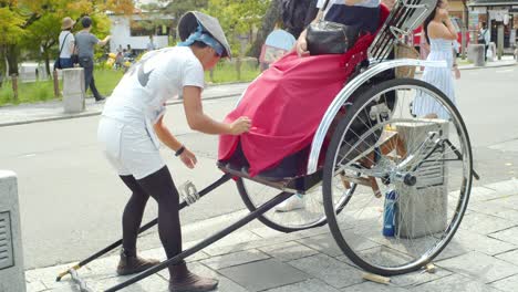 Hombre-Sujetando-Las-Sábanas-Al-Rickshaw-Antes-De-Llevarlos-De-Gira-En-Kyoto,-Japón-Iluminación-Suave-Cámara-Lenta-4k