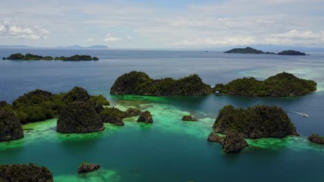 Drone-flying-over-a-group-of-small-tropical-islands-on-the-coast-of-Raja-Ampat,-Indonesia