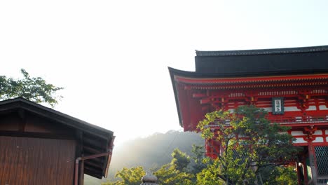 Slide-shot-of-the-sunrise-appearing-from-behind-the-mountains-at-a-temple-in-Kyoto,-Japan-4K-slow-motion
