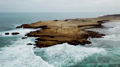 Vista-Aérea-De-Las-Olas-Del-Océano-Salpicando-En-Los-Acantilados-Oscuros