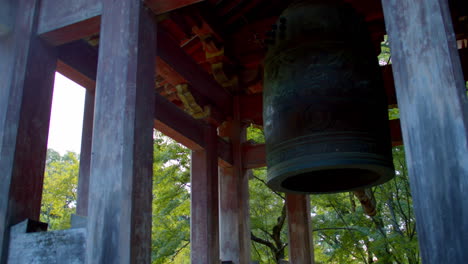 Close-up-shot-of-a-big-Japanses-bell-low-angle,-in-japanses-garden-in-the-background-in-Kyoto,-Japan-soft-lighting