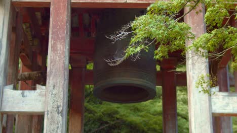Slide-shot-of-an-old-bell-sitting-outside-of-a-temple-in-Kyoto,-Japan-4K-slow-motion