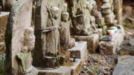 Slide-shot-of-small-stone-statues-outside-of-a-temple-in-Kyoto,-Japan-4K-slow-motion
