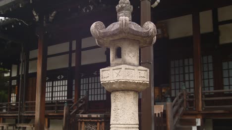 Slide-shot-of-an-old-stone-lamp-in-front-of-a-temple-in-Kyoto,-Japan-4K-slow-motion