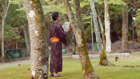 Slide-shot-of-a-person-wearing-a-hakama-standing-in-a-Japanese-garden-in-Kyoto,-Japan-4K-slow-motion