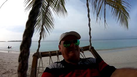 Hombre-Relajándose-En-El-Columpio-De-La-Playa-En-Las-Maldivas