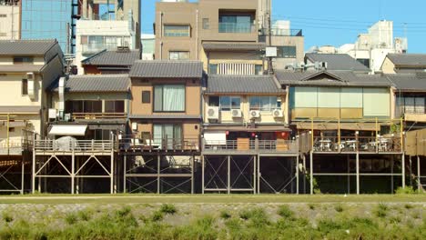 Slide-shot-of-houses-lined-up-along-a-river-in-Kyoto,-Japan-4K-slow-motion