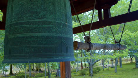 Big-Japanese-bell-surrounded-by-trees-in-a-beautiful-garden-in-Kyoto,-Japan-close-up-soft-lighting