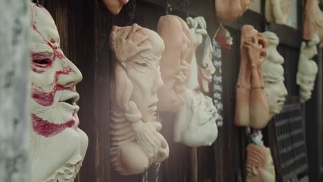 Slide-shot-of-masks-hanging-on-the-wall-in-Kyoto,-Japan-4K-slow-motion