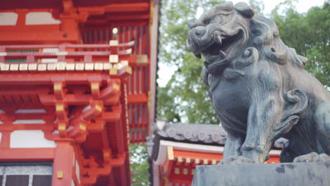 Stone-lion-statue-panning-to-a-beautiful-tall-shrine-early-morning-in-Kyoto,-Japan-soft-lighting