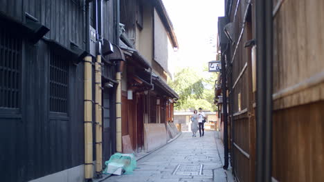 Couple-walking-through-a-Japanese-allyway-early-in-the-morning-in-Kyoto,-Japan-soft-lighting