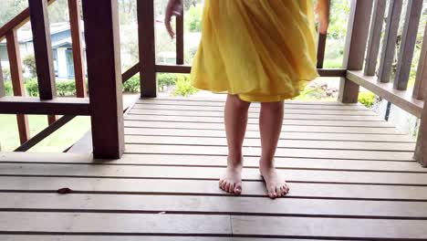 Carefree-and-playful-little-girl-twirling-in-yellow-dress-on-verandah