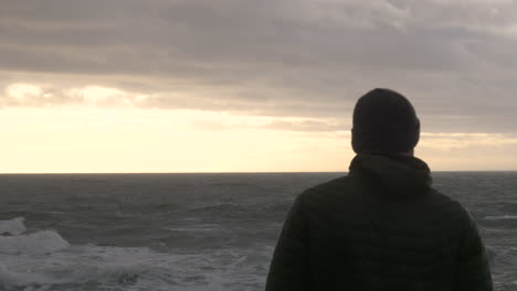Silhouette-Eines-Traurigen-Mannes-Mit-Blick-Auf-Die-Raue-See-Bei-Sonnenuntergang