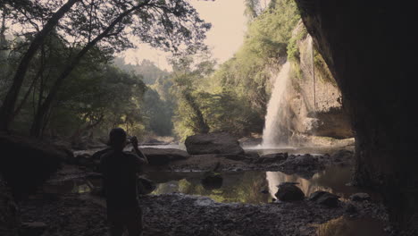 Ein-Junger-Abenteuer--Und-Naturfotograf,-Der-Einen-Wasserfall-Aus-Einer-Höhle-Mitten-Im-Dschungel-Fotografiert