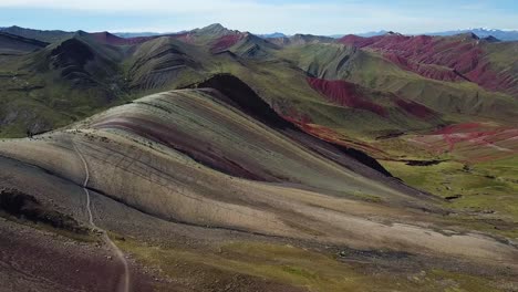 Aerial,-rising,-drone-shot-tilting-over-the-Palcoyo-rainbow-mountain,-in-Valle-Rojo,-or-Red-Valley,-Andes-mountains,-sunny-day,-in-Peru,-South-America