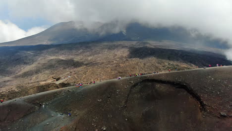 Aerial-dolly-in-atmospheric-view-of-people-hiking-on-volcano-Etna