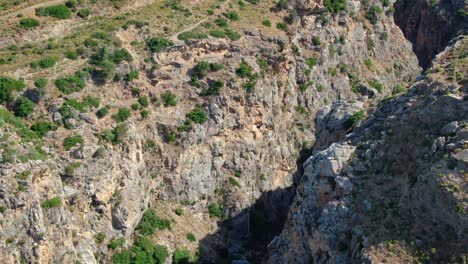 Aerial-over-a-deep-valley-amidst-tall-and-huge-rocky-mountains,-island-Crete,-Greece