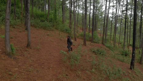 Aerial-shot-tracking-in-front-of-an-African-hunter-stalking-prey-with-a-bow-and-arrow-and-taking-aim-and-shooting