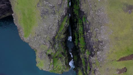 Waterfall-reveal-over-sea-cliff-ravine-gorge-in-Faroe-Islands,-aerial-view
