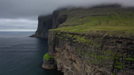 Aerial-flight-along-majestic-clifftops-in-storm-clouds,-Faroe-Islands