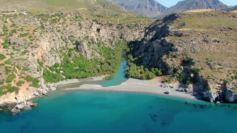 Descent-shot-of-beautiful-blue-bay-and-canyon-on-Crete,-Greece