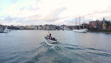 Aerial-shot-of-tourist-boat-sailing-through-old-city-of-Stockholm,-Sweden