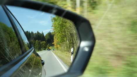 Close-Up-View-of-the-Road-in-the-Rearview-Mirror-of-a-Car
