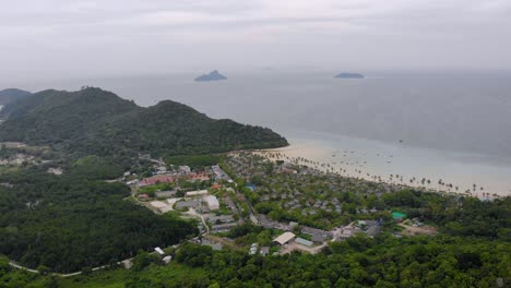 Aerial-panorama-of-a-popular-tropical-island-with-white-sand-beaches-and-lush-green-jungle-on-an-overcast-day