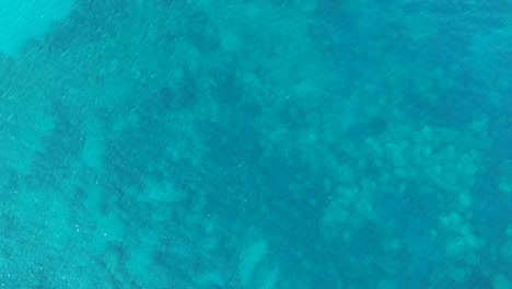 Turquoise-blue-water-with-coral-reefs-below-on-the-island-of-Zakynthos-Greece,-Aerial-drone-lift-view-from-above