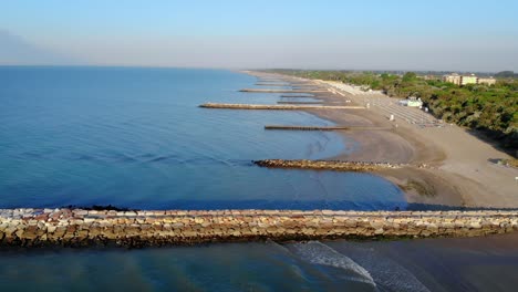Drone-seascape,-blue-water-coast,-inlets,-jetty,-beach,-long-range-view,-Caorle,-Italy