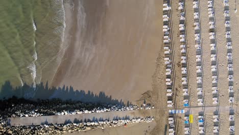 High-aerial-top-down-view-of-jetty,-sand,-many-beach-cabanas-in-a-row,-drone-shot